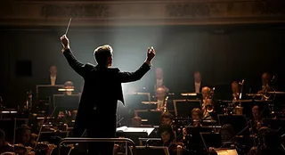 pngtree-conductor-leading-an-orchestra-in-a-dramatic-performance-image_20408277.webp